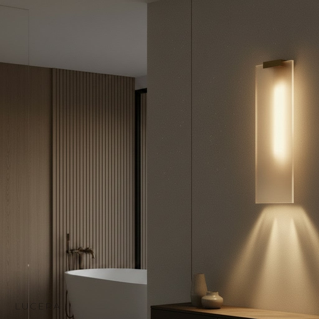 nighttime lifestyle view of marble sconce illuminating dark marble wall in luxury bathroom