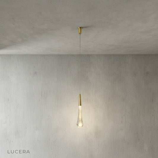 gold-plated aluminum pendant light with crystal bottom against neutral backdrop