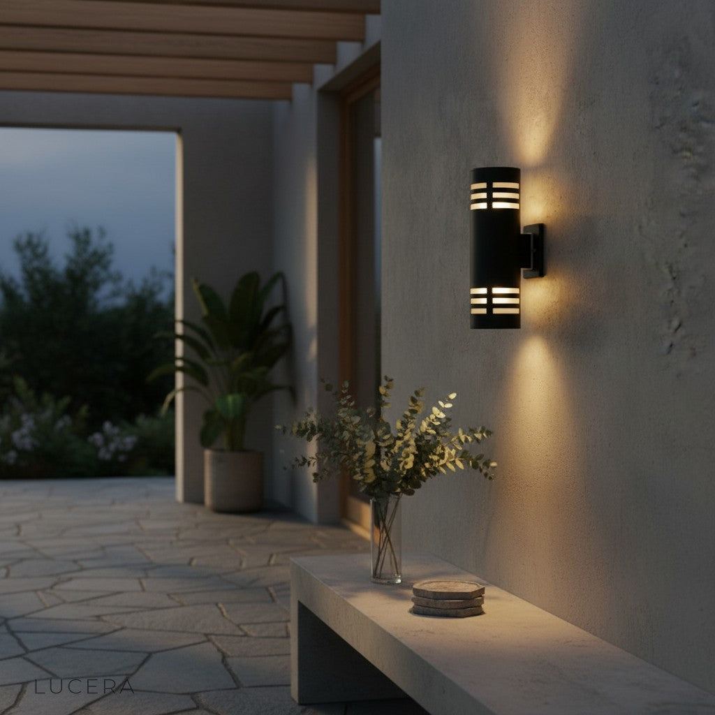 outdoor sconce glowing beside modern entry door with stone texture