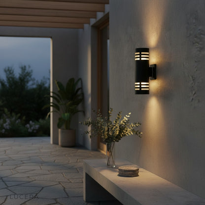 outdoor sconce glowing beside modern entry door with stone texture