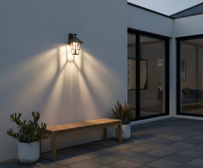 black Portia sconce paired with stone wall and green landscaping for ambient evening light