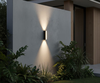 contemporary outdoor wall lamp glowing against dark stucco wall at night