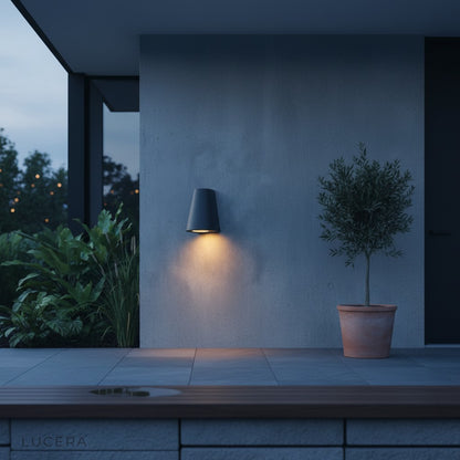 black Avery LED sconce mounted on brick wall with soft 3000K light casting shadows