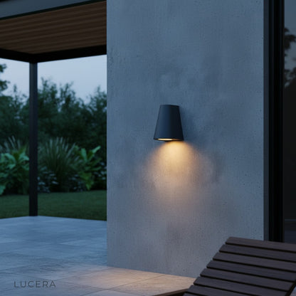 Avery wall lamp glowing warmly beside an entryway door with stone veneer accents