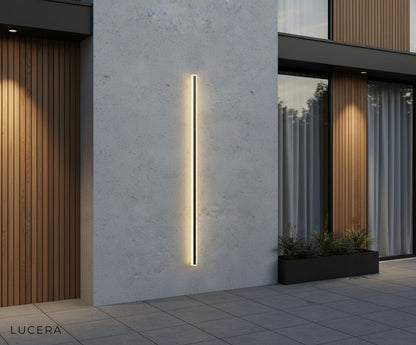 Odette tall outdoor LED wall lamp in black finish paired with stone facade and outdoor sofa
