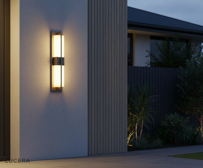 black and copper sconce casting warm light on a dark stucco wall beside an entry door at twilight