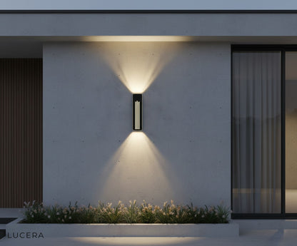 durable black aluminum outdoor light fixture glowing against dark siding in a stylish backyard