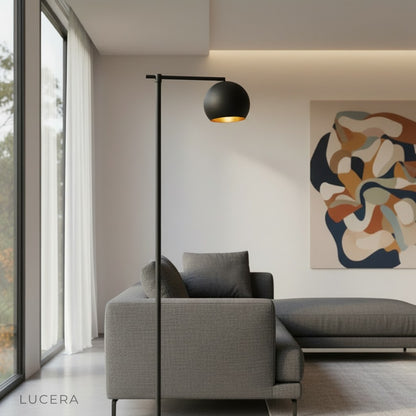 Tanzanite floor lamp in gold finish beside an armchair in bright living room