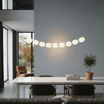 Overhead view of chrome string of pearls pendant chandelier with acrylic orbs reflecting light on dark ceiling