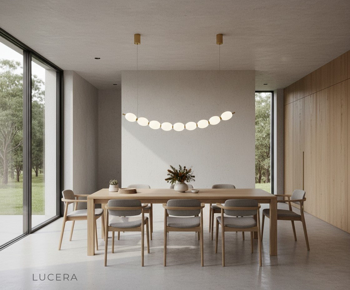 Chrome string of pearls LED chandelier in open-plan kitchen island setting with bar stools and ambient light