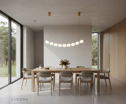 Chrome string of pearls LED chandelier in open-plan kitchen island setting with bar stools and ambient light