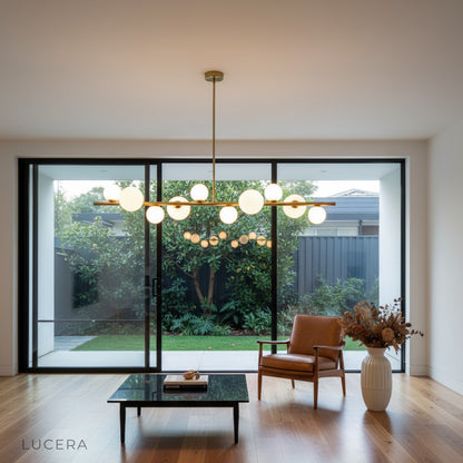 Ran Linear Chandelier glowing above a marble island in an open-concept kitchen dining area