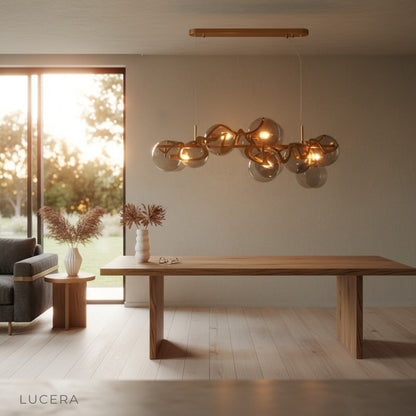 Calmo gold chandelier over dining table at dusk with ambient warm light and shadows