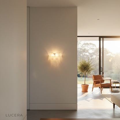 Carme wall sconce in brushed gold finish mounted on textured plaster wall in minimalist hallway