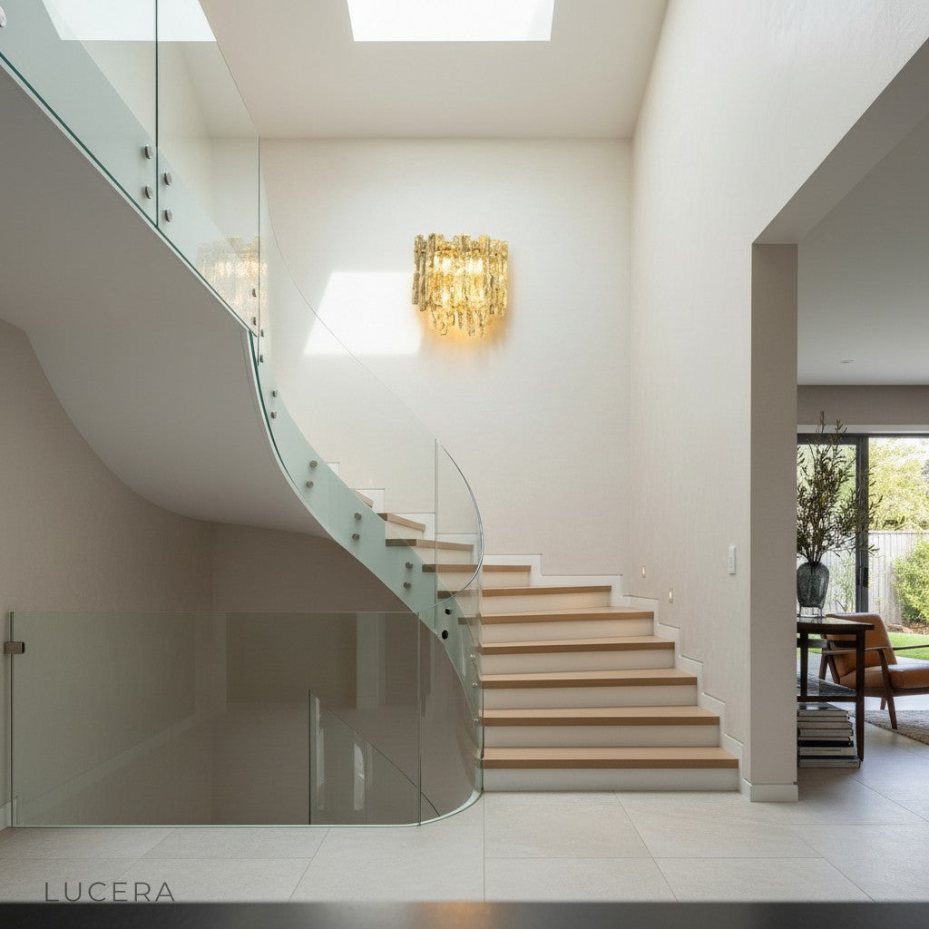 Close-up of Cielo sconce textured glass orb and polished brass arm against plaster wall