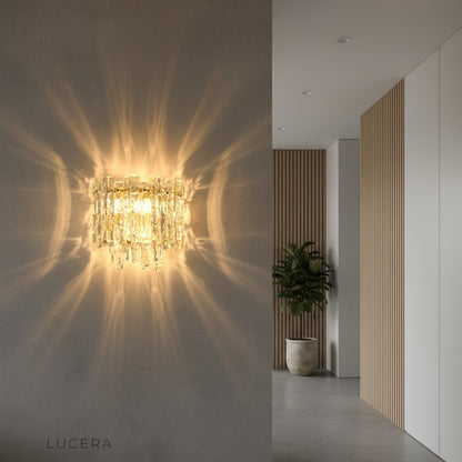 Cielo glass wall fixture illuminated at dusk above a marble console in an entryway