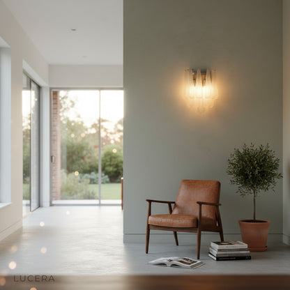 Polished chrome wall sconce with clear textured glass mounted on neutral plaster wall in bright hallway