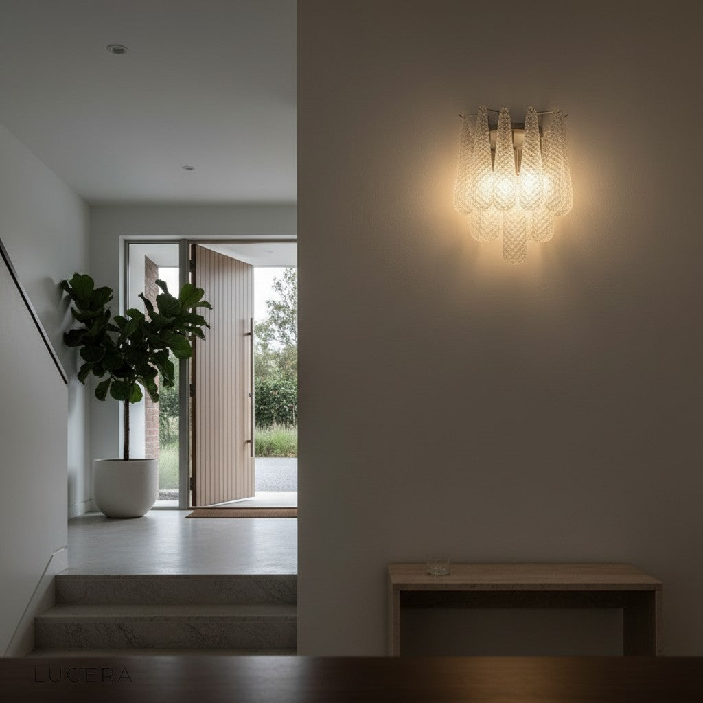 Evening lifestyle shot of textured glass sconce casting warm glow over a cozy reading nook with armchair