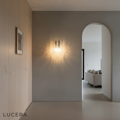 Murano style sconce illuminating a dark accent wall in a sophisticated dining room with candlelight