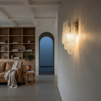 Nighttime ambient shot of glass wall sconce glowing beside a velvet sofa in a stylish lounge setting
