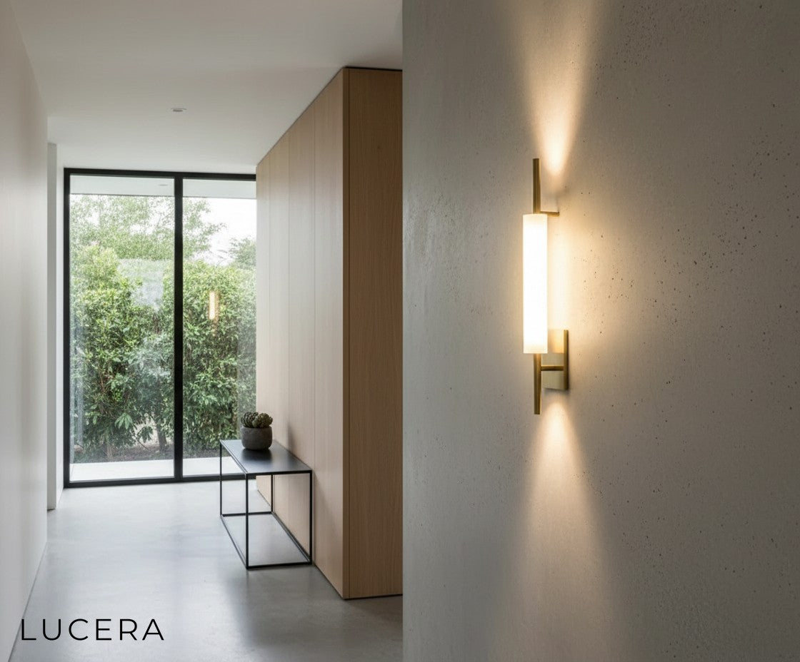 nighttime shot of glass wall sconce glowing warmly against dark textured wall in modern lounge