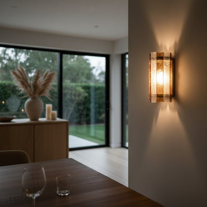 Detail of glass shade refracting warm light against textured plaster wall