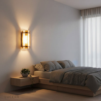 Evening shot of brass wall lamp with candle-like glow in a dimly lit dining room