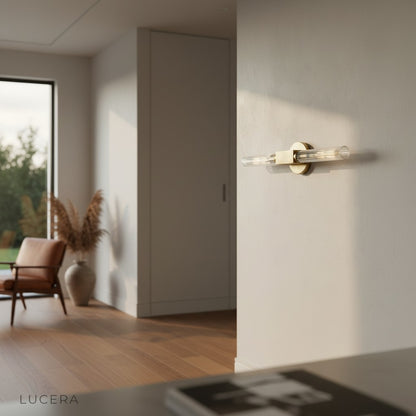 Ravello brass minimalist wall lamp illuminating a cozy bedroom bedside