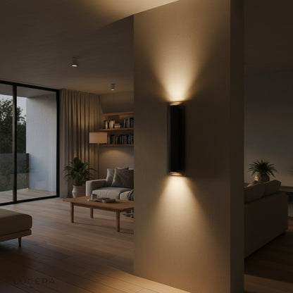 Loano iron wall lamp with warm light in rustic hallway setting at dusk