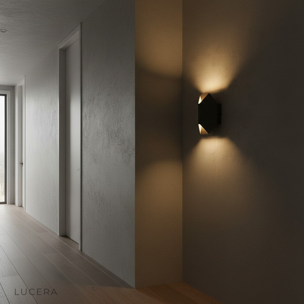 Nappe stainless steel wall lamp at dusk casting warm glow on textured wall