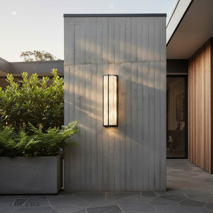 marble wall lamp mounted on a textured plaster patio wall with plants