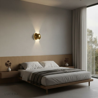 Cool light setting on Lucera brass wall lamp in modern bedroom bedside scene