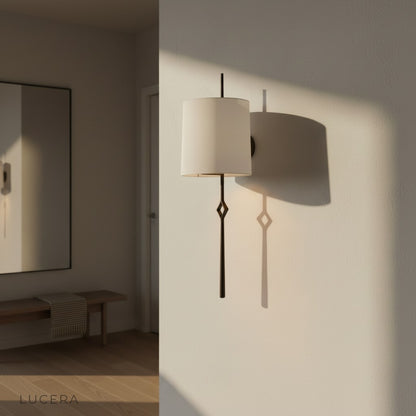 Entasis cloth wall lamp glowing warm light beside sofa in cozy bedroom