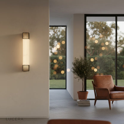 Astragal wall lamp casting warm light over luxury bedroom bedside with marble texture