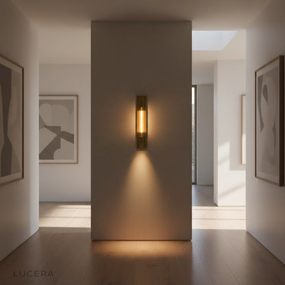 Warm bronze Verve sconce illuminating a modern vanity with marble countertop and brass faucet