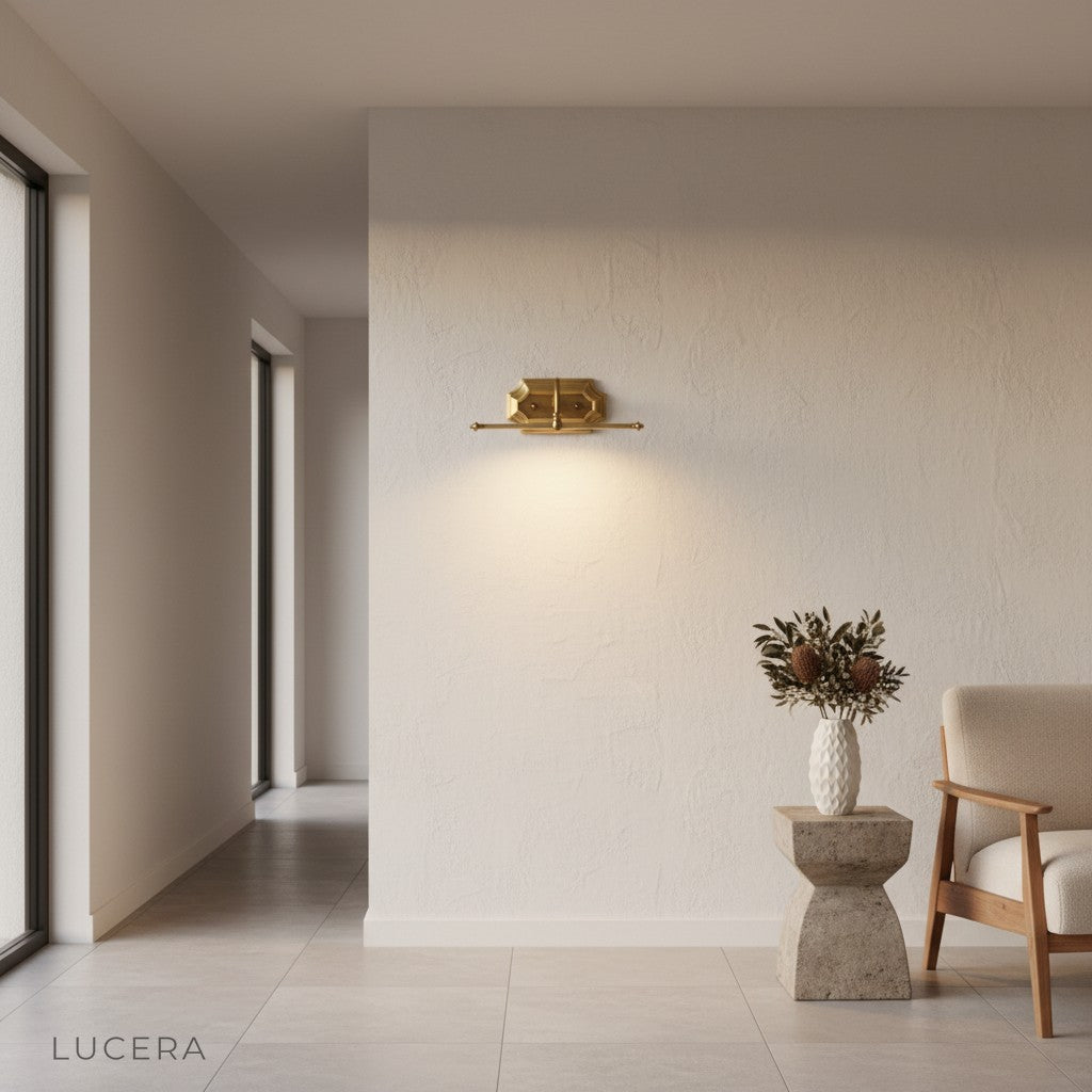 Martellato brass wall lamp casting soft glow in an elegant entryway at dusk