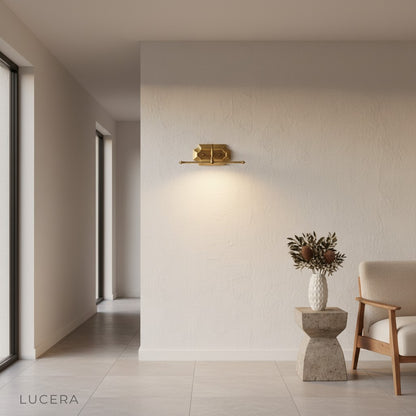 Martellato brass wall lamp casting soft glow in an elegant entryway at dusk