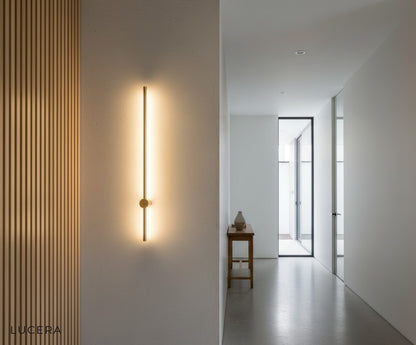 Rinforzando wall light with warm light beam across a hallway mirror
