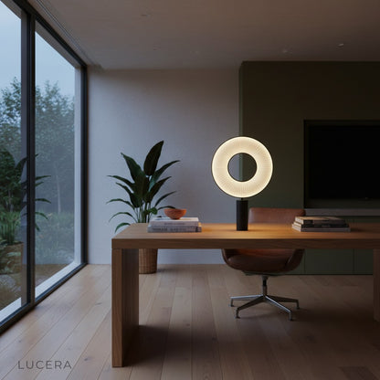 Brio table lamp casting warm ambient light in dark living room corner with armchair and plant