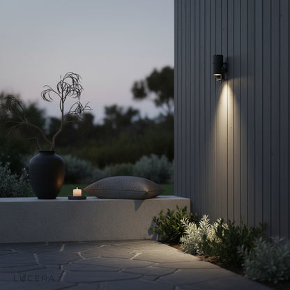 black finish outdoor spotlight mounted on brick wall casting warm light beam