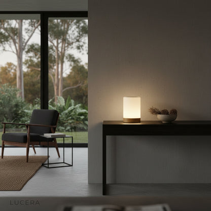 Elegant Janus Table Lamp illuminating a reading nook with a linen armchair and plants