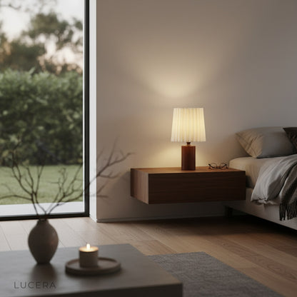 Pandora Table Lamp in modern bedroom with neutral bedding, showing brass accents against cream linen shade