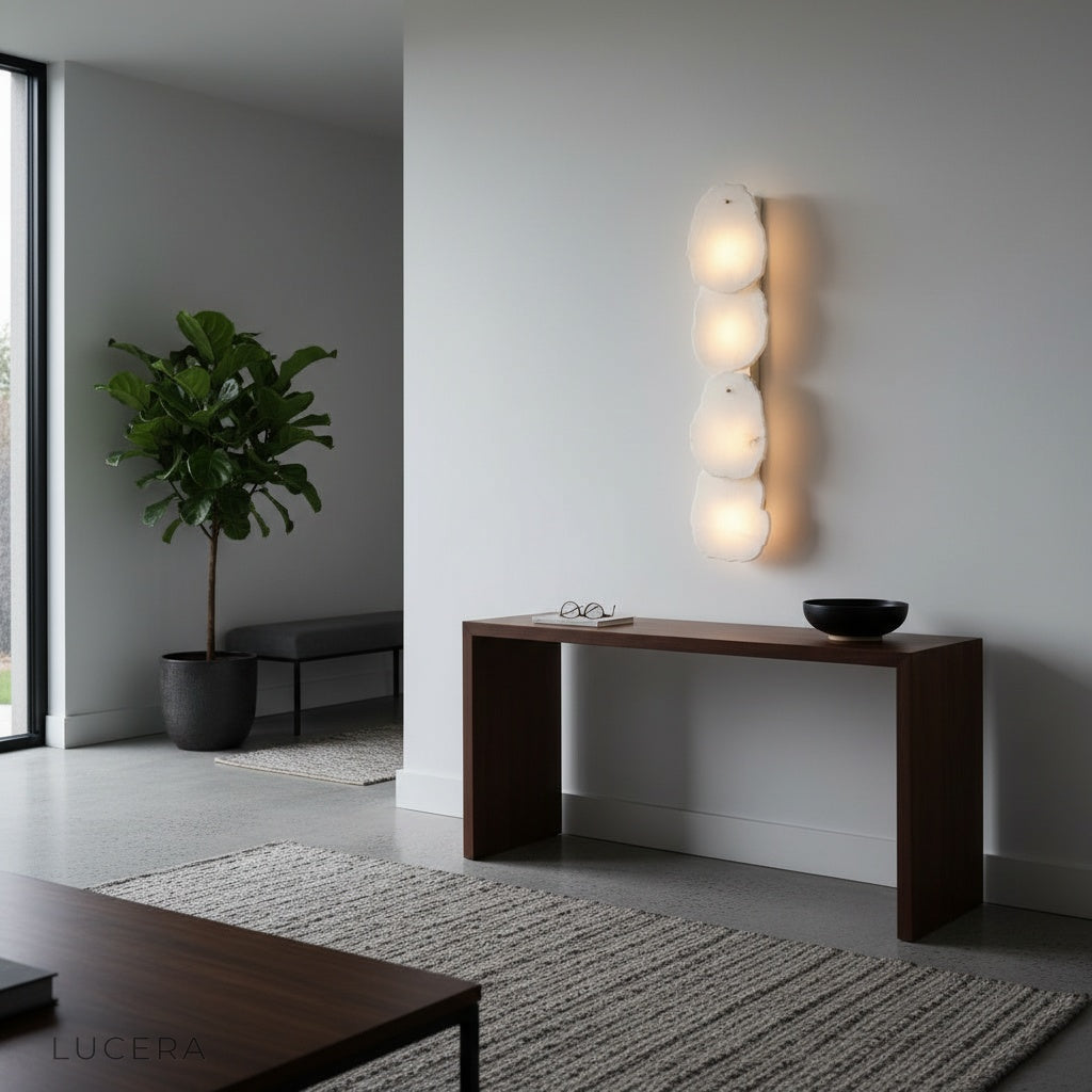 Esker wall lamp above a bedside table casting warm light in a minimalist room