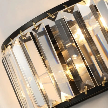 close-up detail of gold crystal wall lamp showing sparkling glass prisms and iron frame