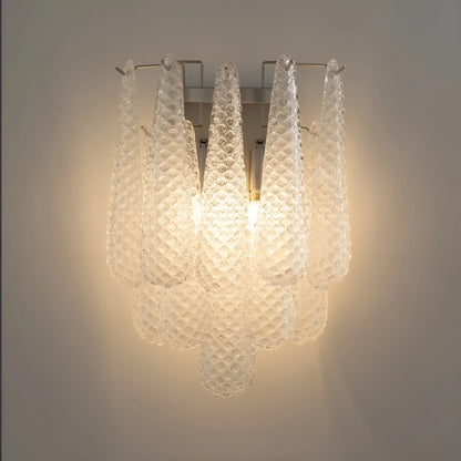 Close-up of textured glass surface refracting warm light with visible bubbles and swirls, chrome fixture detail