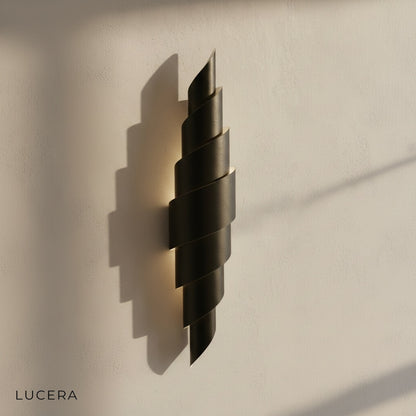 Close-up detail of Crux sconce leather stitching and matte black iron arm against a neutral wall