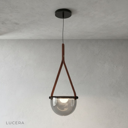 Glimmer leather strap pendant light centered on a clean white studio background