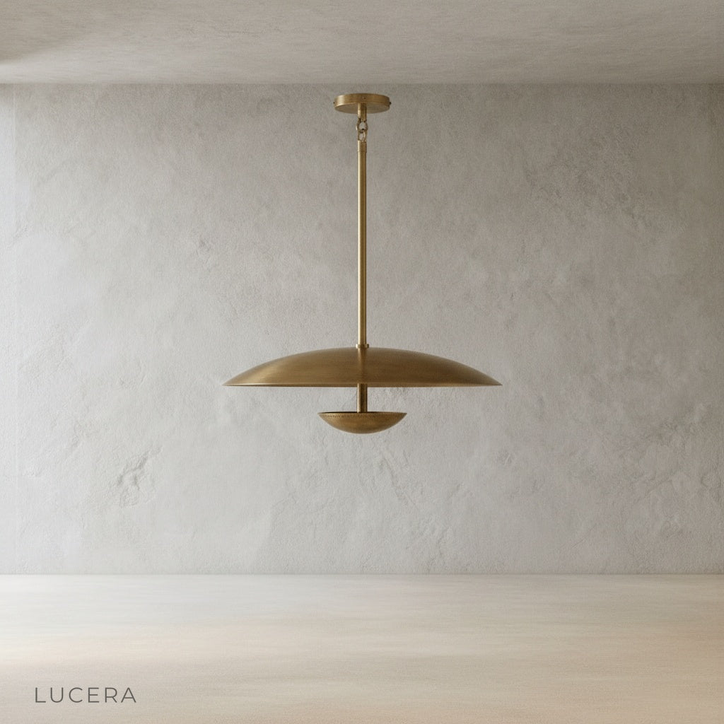 minimalist studio view of Ravish sculptural brass disc pendant light showing smooth curved shade