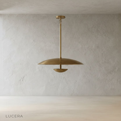 minimalist studio view of Ravish sculptural brass disc pendant light showing smooth curved shade