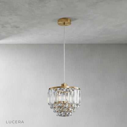 Front view of crystal diamond pendant light with brass hardware against gray studio backdrop